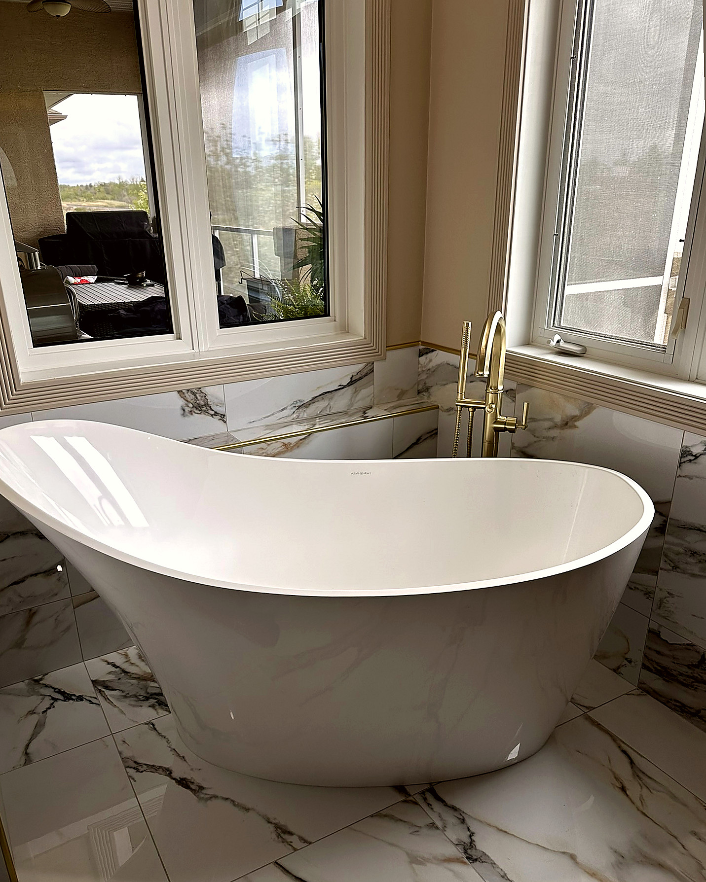 White freestanding tub against marble-pattern wall tile, with a glass shower beside it.