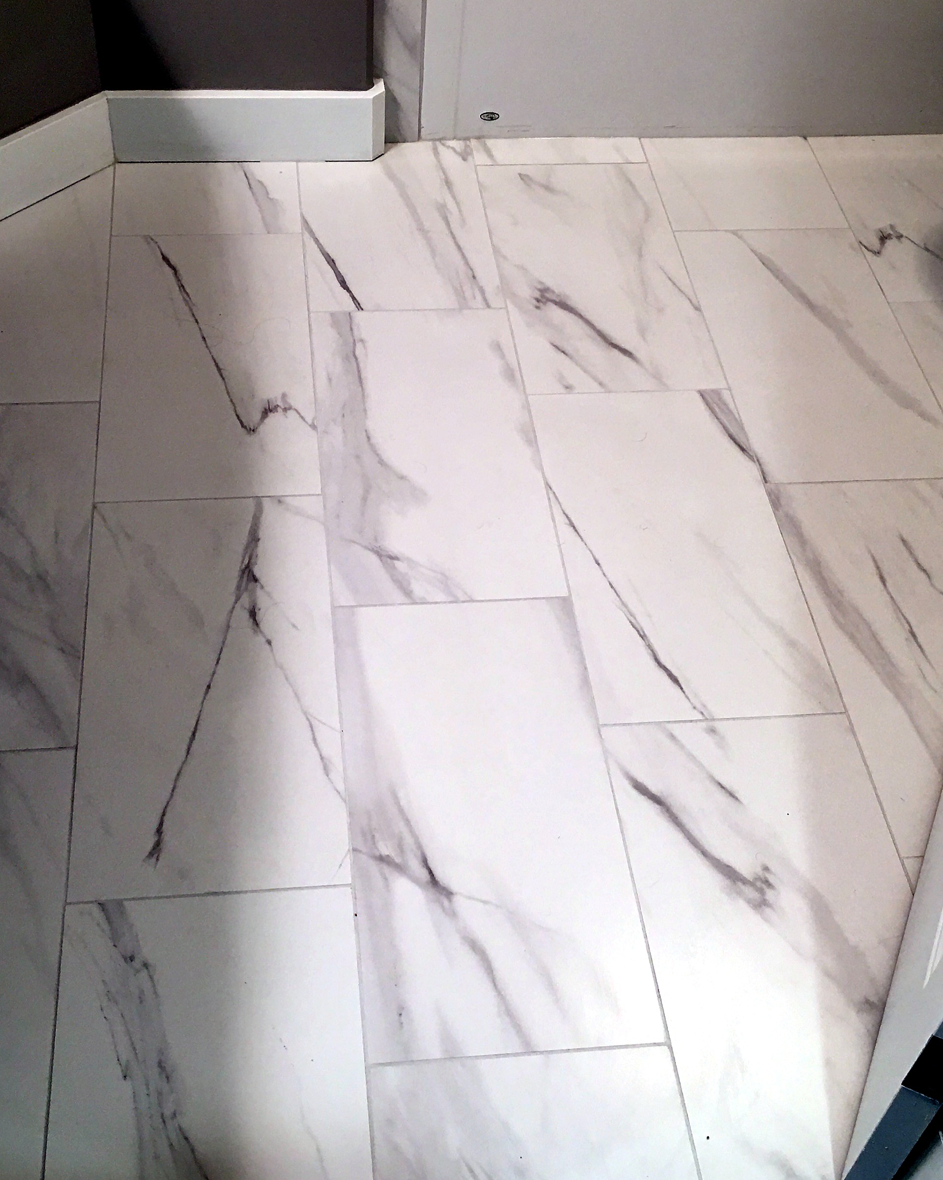 Bathroom with marble-pattern floor tile, a floating vanity, black faucet, and a glass shower.