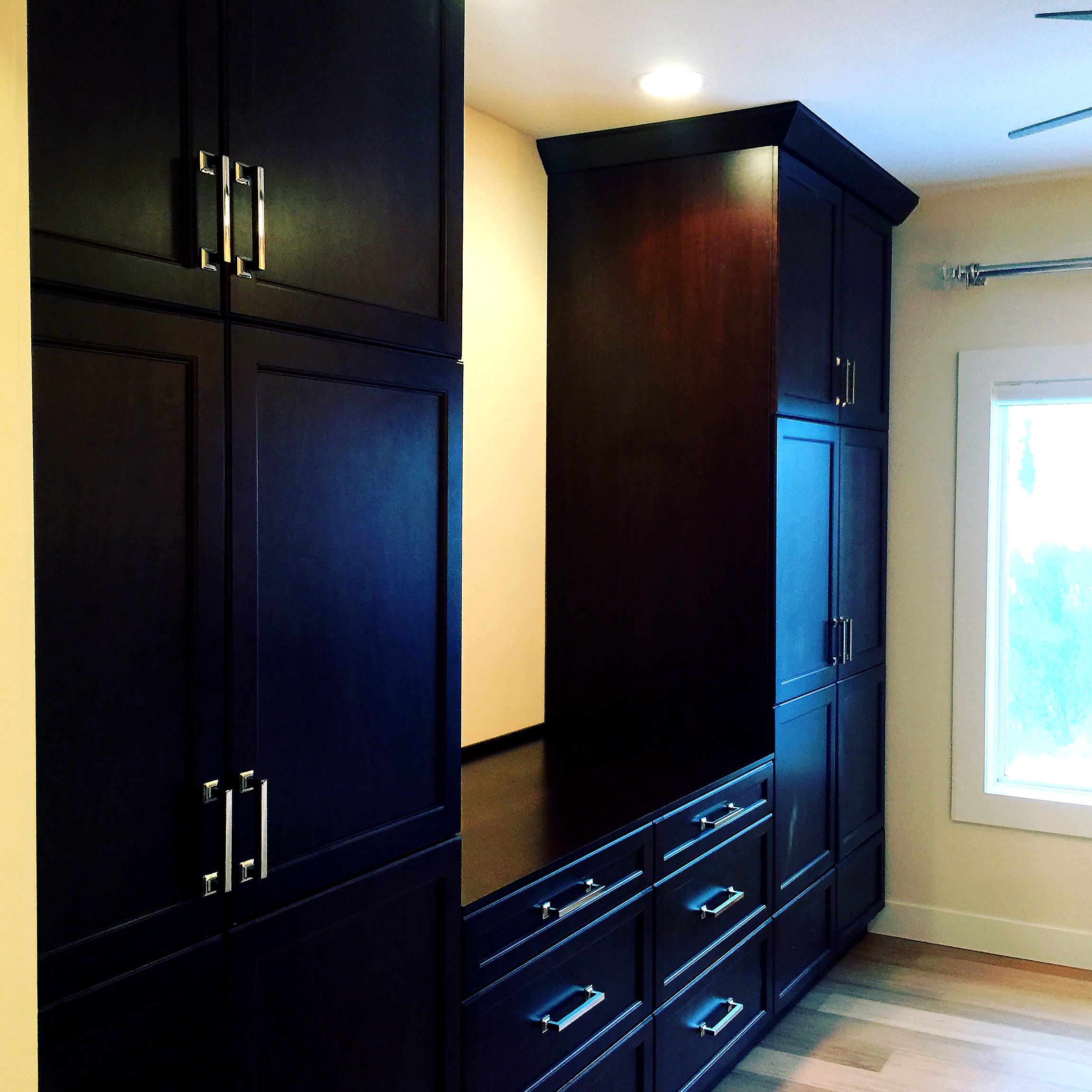 Tall dark wood cabinet with gold handles, next to open wooden shelves.